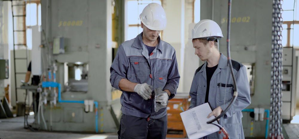 Two men inspect parts in a factory.