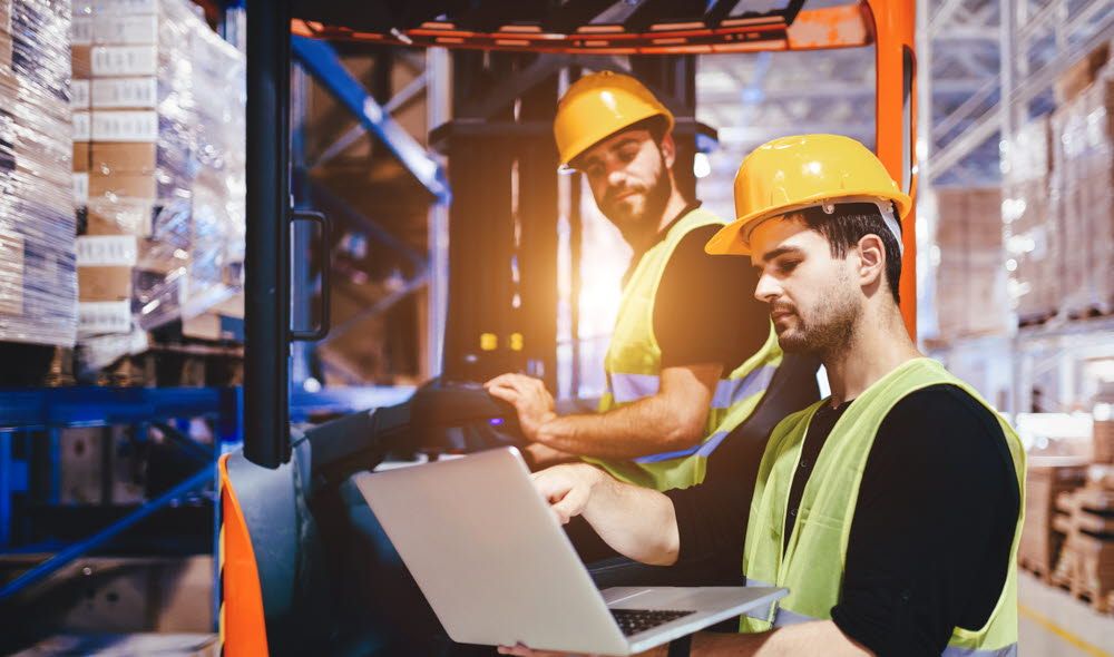 Two men are working in the factory, checking their computers.