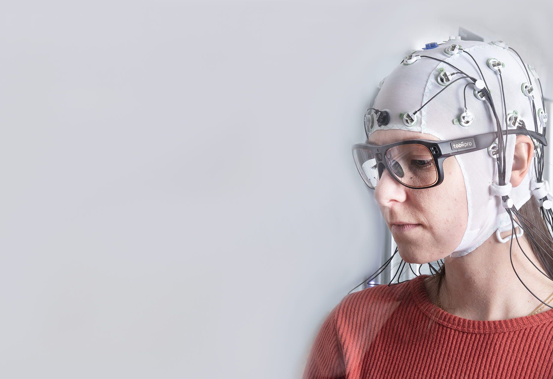 Woman wearing Tobii Pro Glasses 3 and Brain products cap