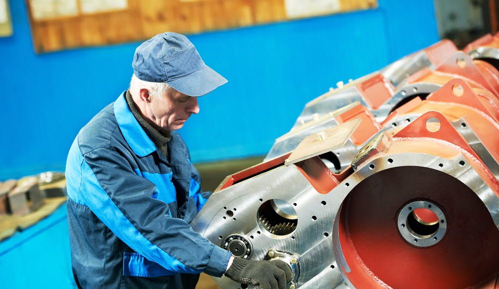 A man adjusting the machine in a factory.