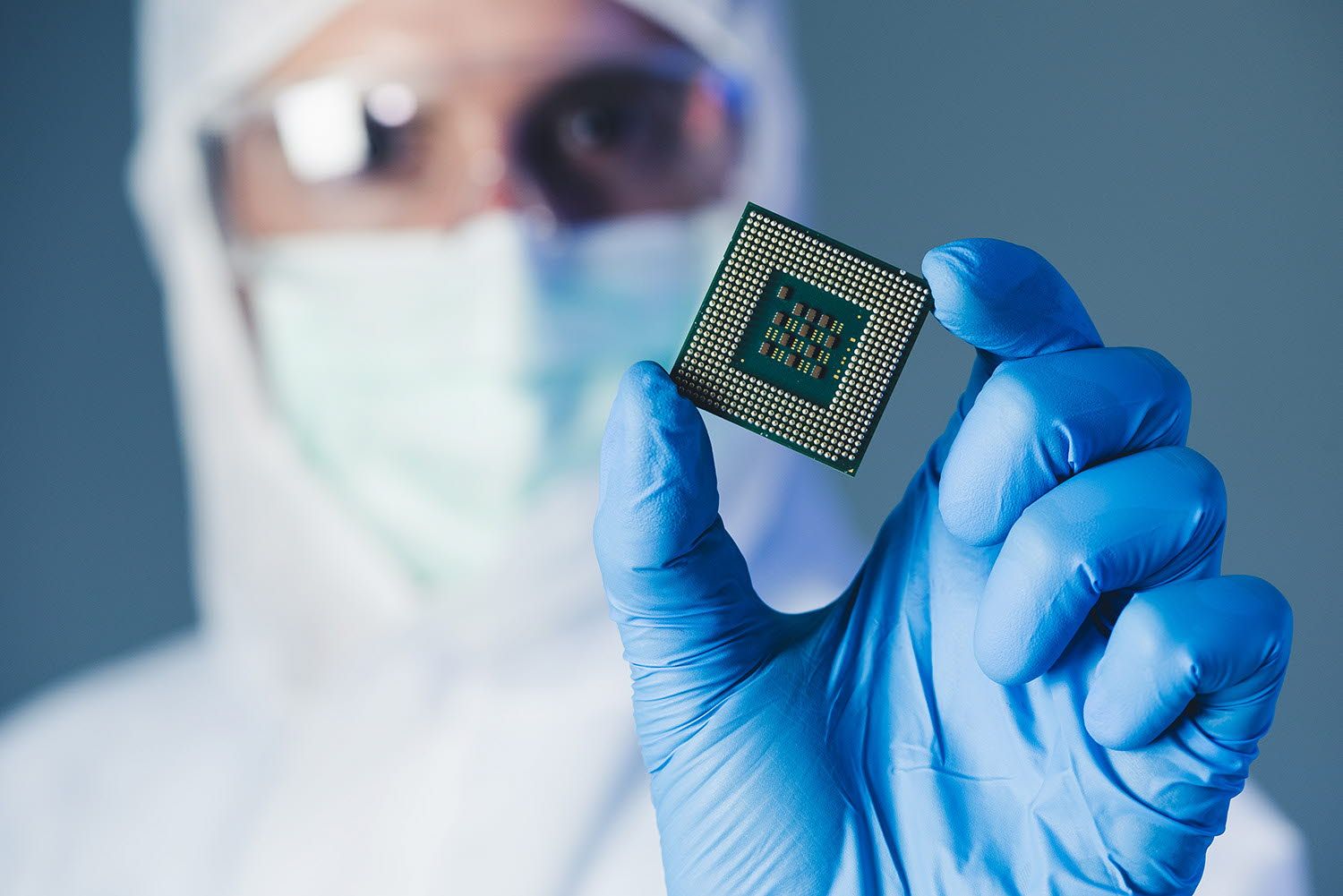 A worker holds an electronic component in his hand for inspection.