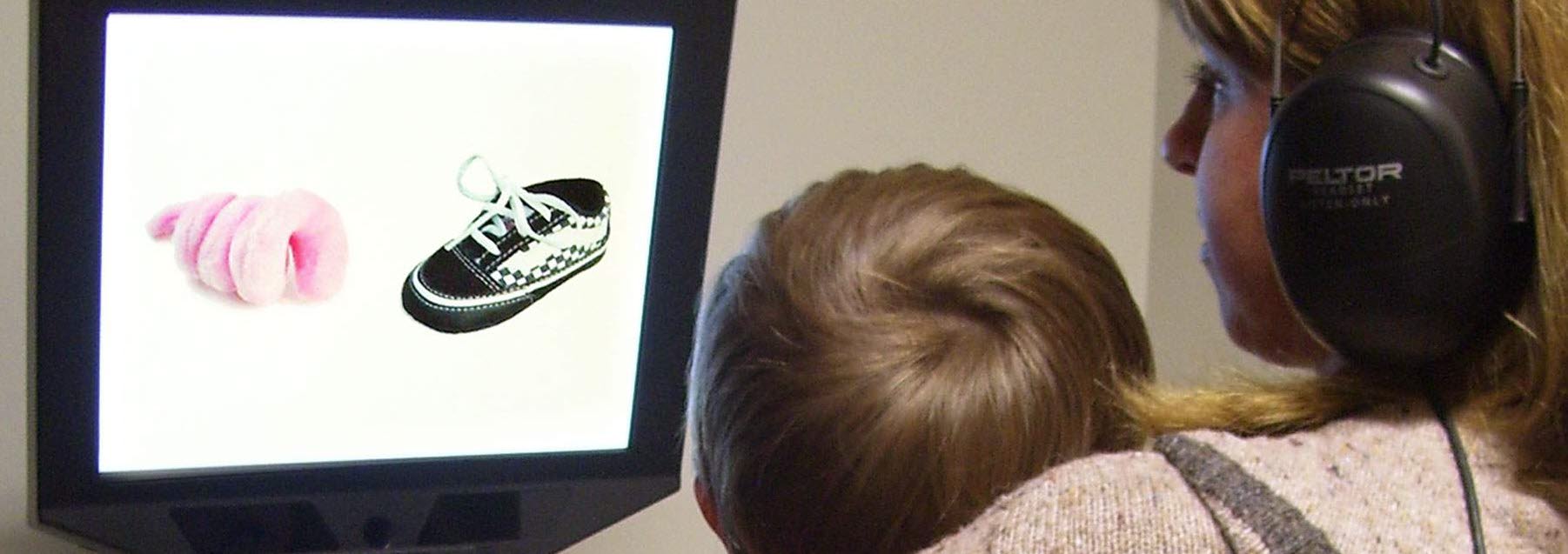  A toddler sitting on his mom’s lap watches the  disfluency study movie on the Tobii Pro screen based eye tracker.