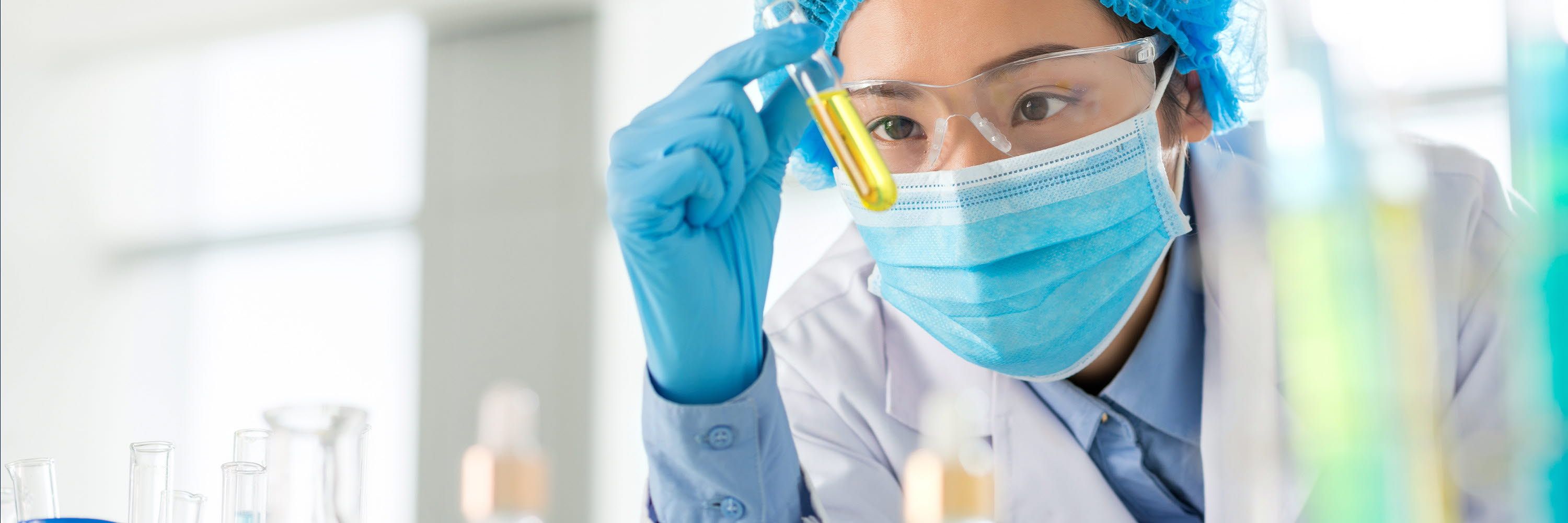 A female inspector visually inspects a test tube.