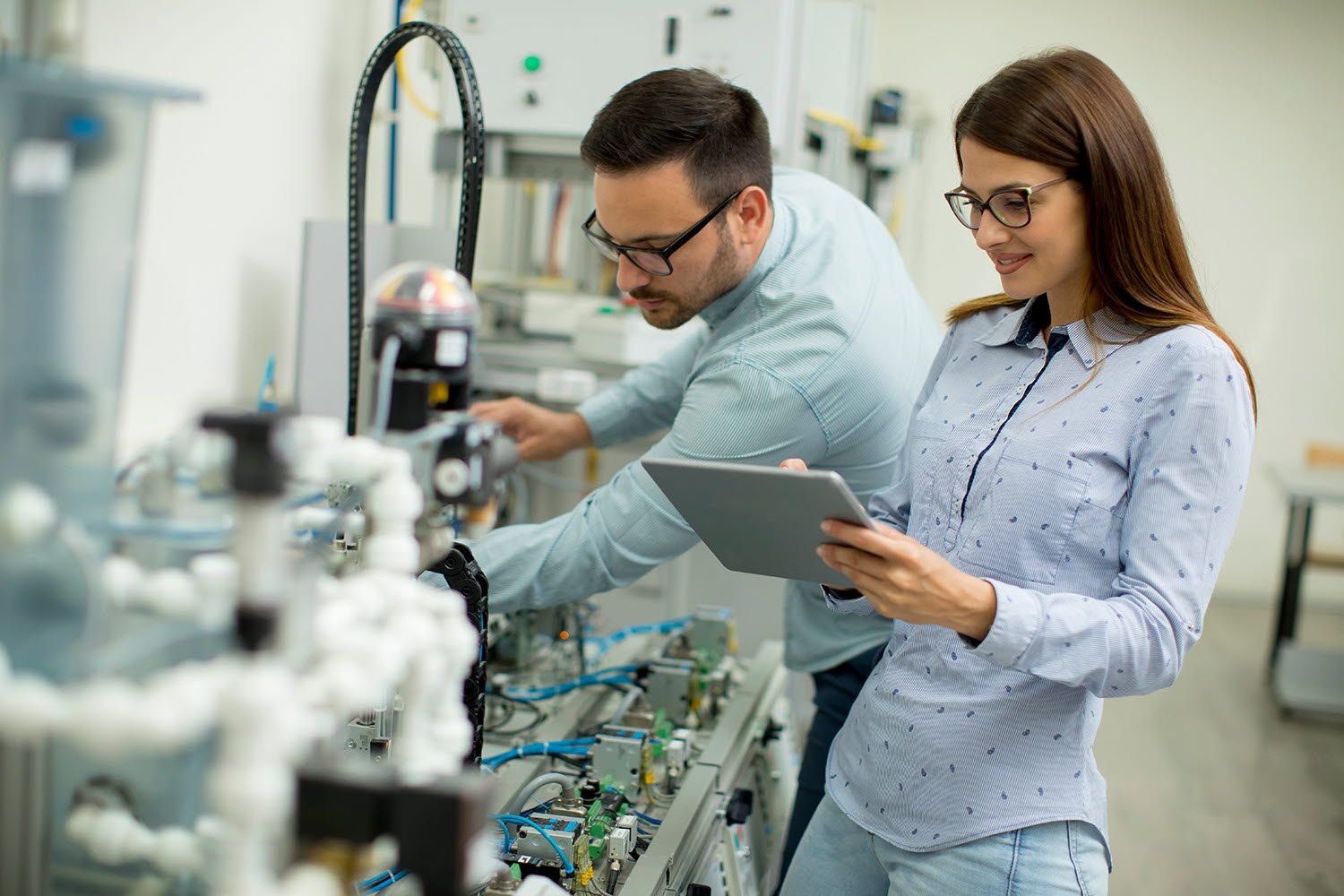 Two workers are setting up electronic component manufacturing equipment.