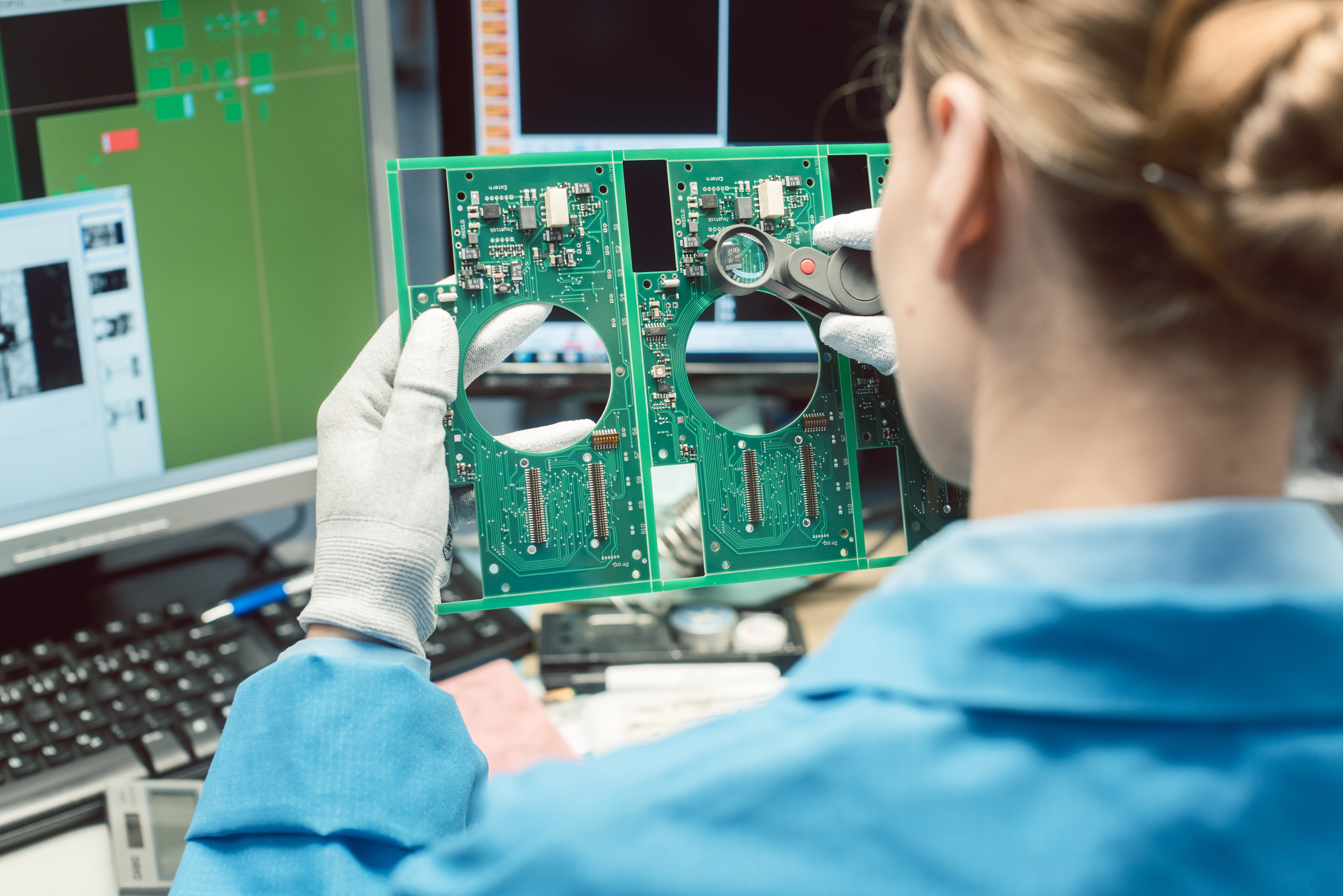 woman visually inspecting electronic circuit board