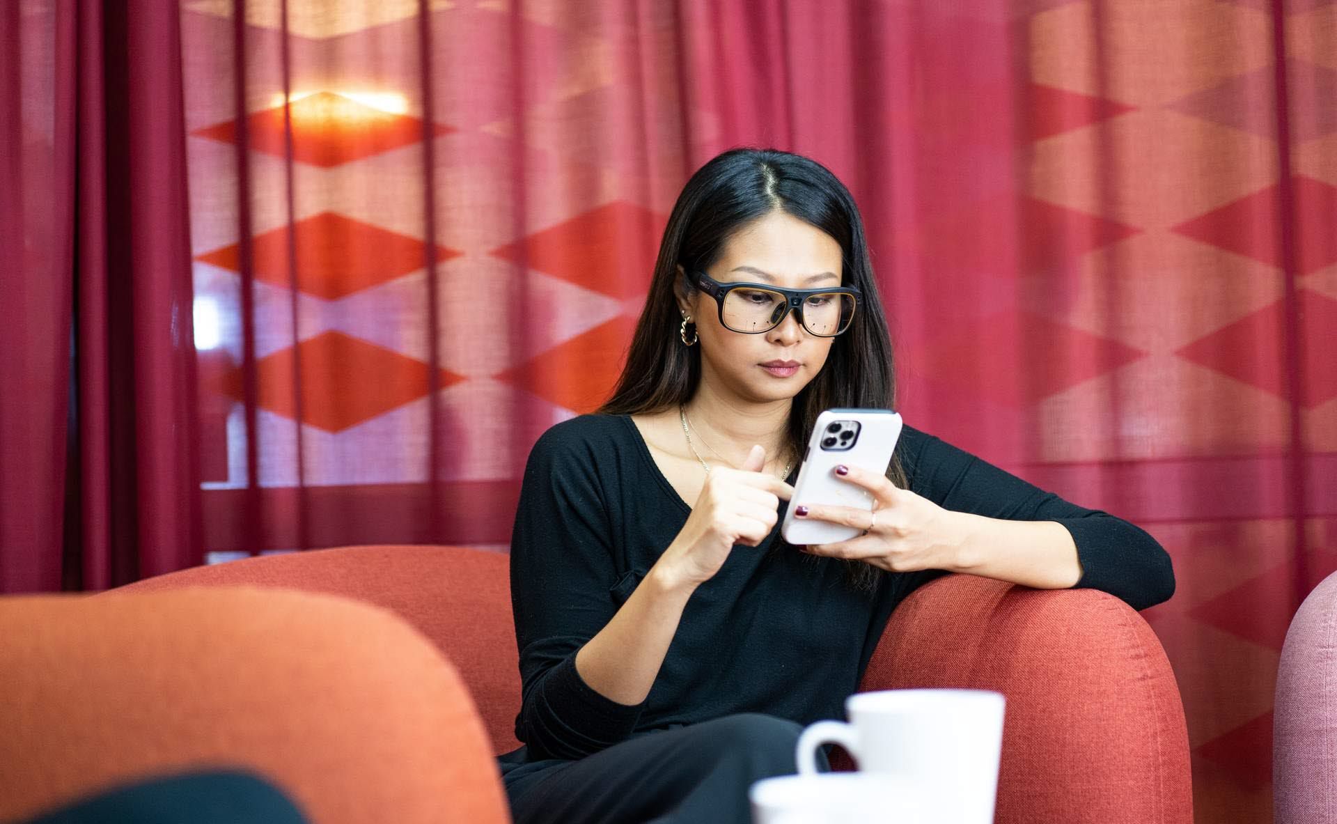 Woman using Tobii Pro Glasses 3 looking at mobile phone