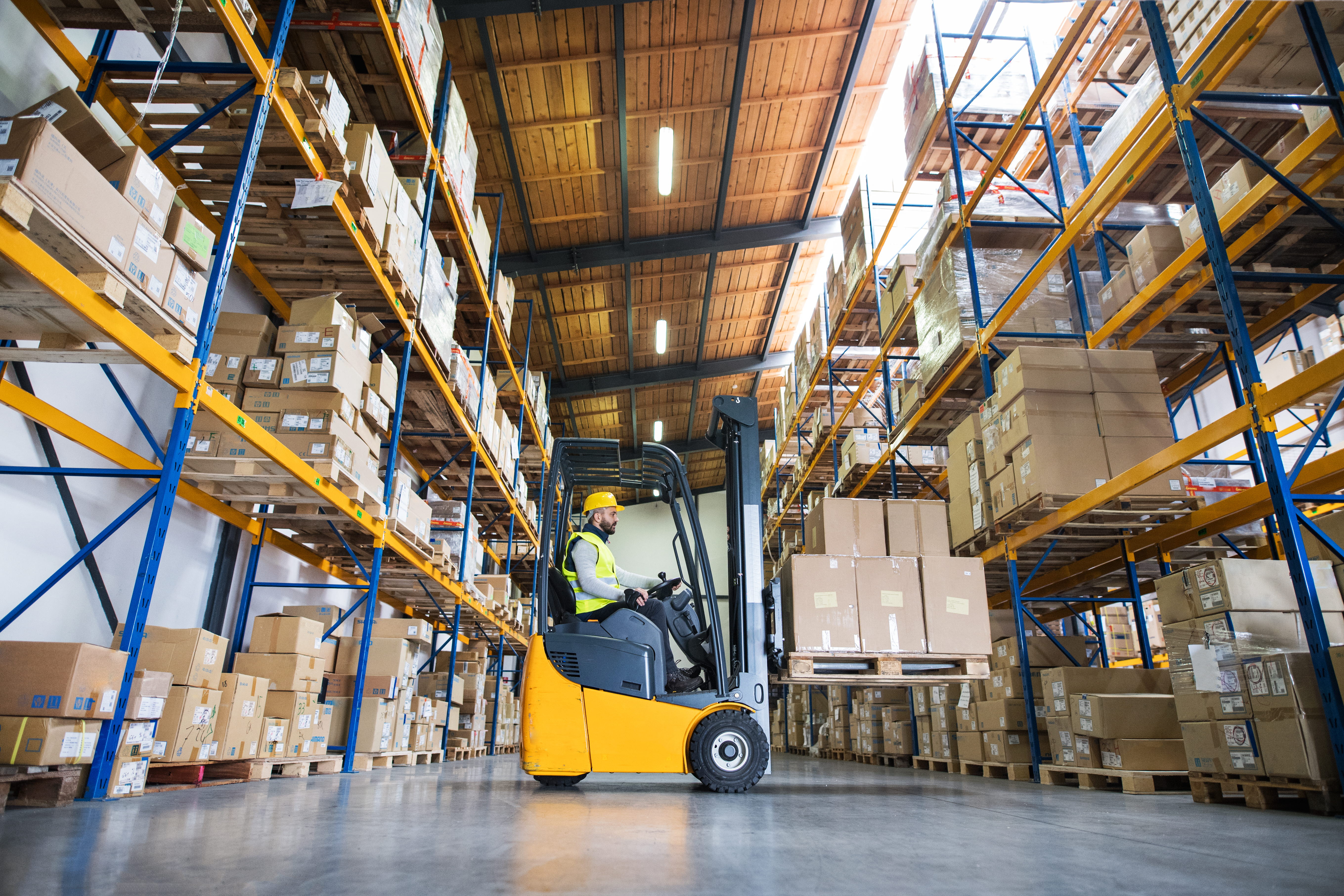 A man is driving a forklift in a warehouse.