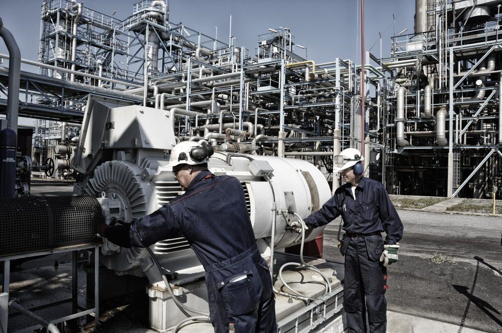 Two workers are inspecting equipment installed outside the power plant.